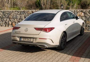 Gaziveren Kıbrıs Rum Kesimi -28.02.2025 Şık lüks bir sedan, zarif tasarımını ve güneşli gökyüzünün altında ince tozunu sergileyerek doğanın arasında sessizce oturuyor.