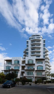 Çarpıcı beyaz bir bina gururla duruyor kabarık bulutların ve masmavi gökyüzünün arka planına canlı bir şekilde..