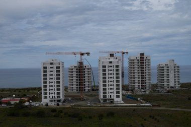 Yeni yerleşim kuleleri dramatik bir gökyüzüne karşı yükseliyor. Okyanus kıyısındaki bir topluluktaki ilerlemeyi gözler önüne seriyor..