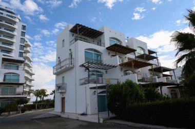 Çağdaş binalar, yemyeşil yemyeşil ve rahat kıyı atmosferiyle çevrili çarpıcı bir gökyüzüne karşı duruyor..