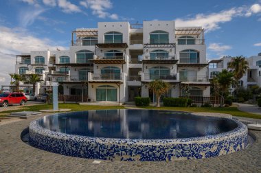 Canlı bir havuz, çağdaş binaların yakınındaki akşam gökyüzünü yansıtır ve sahil kenarında huzurlu bir kaçış yaratır..