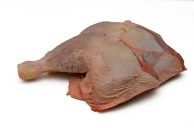 Büyük, çiğ bir tavuk budu beyaz bir yüzeye uzanıyor, baharat ve yemek yapmayı bekliyor, ince dokusunu sergiliyor..