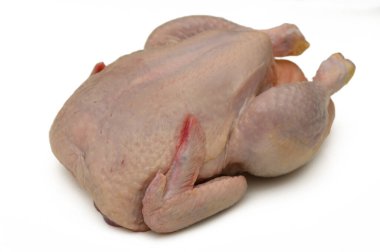 Bütün tavuk baharat ve yemek yapmayı bekliyor. Güneşli bir mutfak ortamında canlı pembe deri sergiliyor..