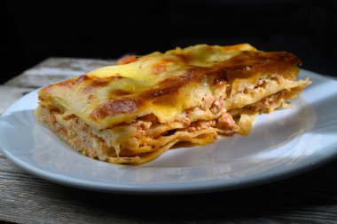 Lezzetli bir ev yapımı lazanya tabakası. Kaliteli ahşap bir yüzey üzerinde peynir ve et katmanları sergiliyor..