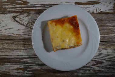 Lezzetli bir kare fırınlanmış güveç beyaz bir tabakta oturur ve akşam yemeğinde sıcak bir yemek için davet eder..