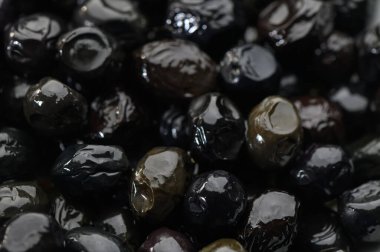 Parlak siyah zeytinler canlı yüzeylerini sergiliyor, zengin lezzet ve dokularla tabakları yükseltmek için bekliyorlar..