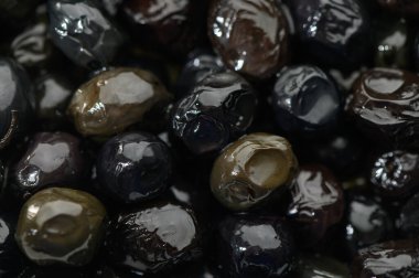 Parlak siyah zeytinlerin yakın plan görüntüsü zengin dokularını gösterirken mutfak lezzetleri için seçilmeyi bekliyor.