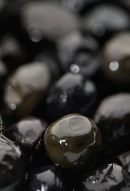 Parlak siyah çakıl taşları parıldar, ışığı yansıtır ve doğanın güzelliğini gösteren sakin bir ortam yaratır..