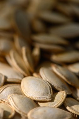 Yakından bakınca taze toplanmış balkabağı tohumlarının narin dokusunu ve ılık tonlarını doğal ışık altında gösterir..