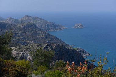 Yumuşak dalgalar engebeli kayalıklara çarparken, canlı yeşillikler güneşli Akdeniz kıyılarını çevreleyecek..