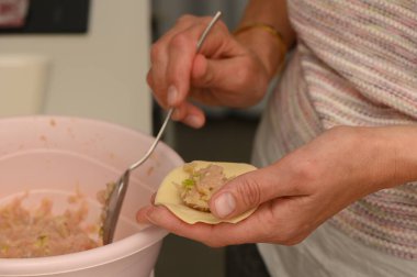 Eller dikkatlice hamuru sıcak bir mutfakta tuzlu bir karışımla doldurur. Mutfak geleneklerini ve aile tariflerini korur..