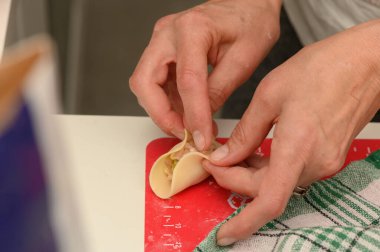 Yetenekli eller, taze malzemelerle dolu hamur köftelerini ustalıkla katlarken sıcak bir mutfak etkinlikle uğulduyor..