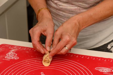 Eller becerikli bir şekilde hamur köftesi ambalajlarını katlar, canlı bir mutfak ortamında aşçılık geleneklerini canlı tutar..