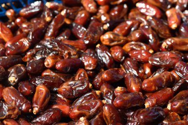 Taze toplanmış tarihler canlı bir pazarda güneş ışığında parlıyor, zengin renklerini ve dokularını sergiliyorlar..