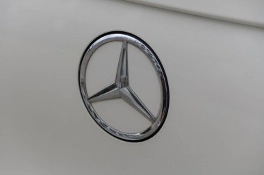 Gaziveren Kıbrıs Rum Kesimi -17.03.2025 Mercedes-AMG Cilalı gümüş amblem alacakaranlığın ılık tonlarını yakalayarak sakin bir yerleşim alanında lüks otomobil işçiliğinin zarafetini vurguluyor.