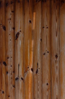 Güzel işlenmiş ahşap kalaslara, yumuşak, sıcak ışıkla vurgulanmış zengin tahıl desenlerine ve düğümlerine detaylı bir bakış, bir huzur hissi uyandıran kırsal bir arka plana karşı kurulmuş..