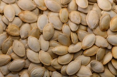 Sonbaharın zengin renklerini yansıtan çok sayıda soluk balkabağı tohumu kırsal bir ahşap yüzeye saçılmış. Mevsimlik toplantıların sıcak özü havayı dolduruyor..