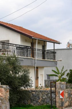 Samimi bir evde, gün ışığında huzurlu bir kentsel alana yerleştirilmiş yeşilliklerle süslenmiş sevimli bir balkon bulunur..