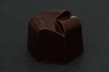 Güzel tasarlanmış bir çikolatalı trüf, parlak dış görünüşü ve karanlık bir yüzeyde zarif bir şekilde duruyor..