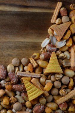 Canlı bir abur cubur karışımı ahşap bir kaseyi doldurur, bir dizi doku ve tat sunar. Kıtır kıtır ve fındıklar birleşerek, toplanma için mükemmel bir görsel ziyafet yaratıyor..