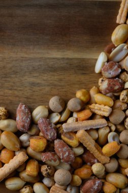 Kırsal ahşap bir tahtada sergilenen lezzetli bir abur cubur karışımı. Çeşitli şekiller, renkler ve dokular, toplantılarda paylaşmak için mükemmel bir ziyafet yaratıyor..