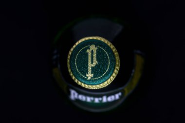 Gaziveren Kıbrıs Rum Kesimi -12,03,2025 Su Perrier. Benzersiz bir amblem içeren yeşil bir şişe kapağı, zarif tasarım ve dokusunu vurgulayarak yumuşak ışığı yakalıyor..