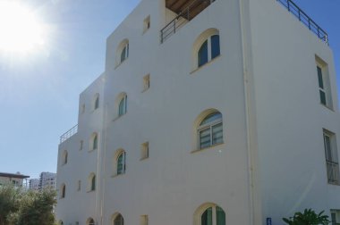 Öğle güneşinin altında eşsiz kemerli pencereler ve sakin bir atmosferi olan güzel bir bina duruyor..