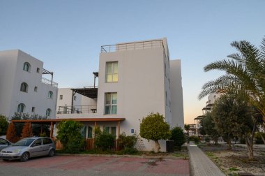 Zarif beyaz binalar alacakaranlığın yumuşak parıltısında güneşleniyorlar, modern tasarım ve sakin bir çevre sergiliyorlar..