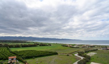 Yuvarlanan yeşil alanlar, engin gökyüzünün altında sakin bir manzara yaratarak kıyı şeridini karşılıyor..