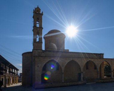 Huzurlu bir köydeki tarihi taş binaların üzerinde gün ışığı parıldıyor. Karmaşık detaylar ve sükunet vurgulanıyor..