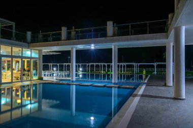 Yumuşak ışıklar altında ışıl ışıl parlayan şık bir havuz. Sıcak bir gecede rahatlamaya ve akşam toplantılarına davetiye çıkarıyor..