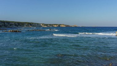 Güneş denizin üzerinde ılık bir parıltı yayıyor dalgalar yavaşça kumlu kumsala yuvarlanırken..