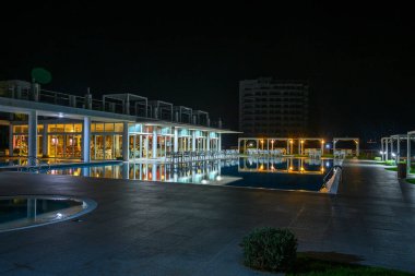 Yumuşak ışıklar sakin bir havuz alanını aydınlatır, gecenin sakinliğini yansıtır ve pitoresk bir ortam yaratır..