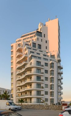 Çarpıcı çok katlı bir bina, çağdaş mimari özelliklerini sergileyerek, akşam gökyüzüne karşı dimdik ayakta duruyor..