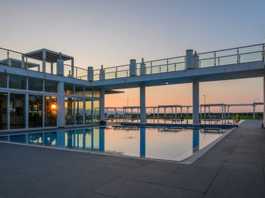 Sakin atmosfer, güneş batarken çağdaş bir havuz alanını sarar ve suya sıcak yansımalar yapar..