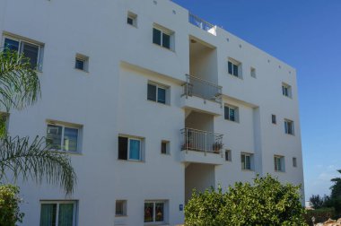 Parlak beyaz yapı parlak yeşil yaprakların yanında berrak mavi bir gökyüzünün altında zarif bir şekilde duruyor..