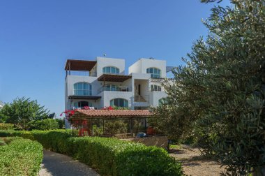 Güzel bir villa canlı yeşilliklerin arasında duruyor, kıyı şeridinin yakınındaki sıcak güneş ışığının tadını çıkarıyor..
