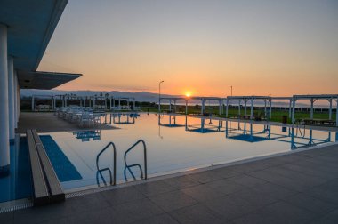 Gün batımları, ışıldayan bir havuzun üzerine sıcak bir parıltı yayar ve okyanus kenarında huzurlu bir atmosfer yaratır..