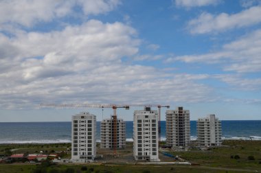 Yeni yerleşim kuleleri kıyı şeridi boyunca yükseliyor, canlı mavi gökyüzüne karşı modern mimariyi sergiliyor..