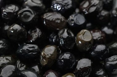 Parlak siyah zeytinler canlı yüzeylerini sergiliyor, zengin lezzet ve dokularla tabakları yükseltmek için bekliyorlar..