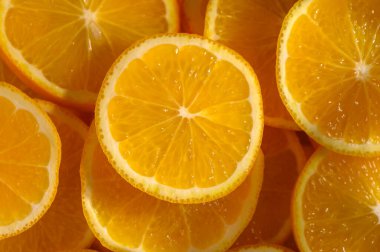 Renklerle dolup taşan taze portakal dilimleri birbirine yakın bir şekilde istiflenir. Sıcak güneş ışığı altında tazelik yayarlar..