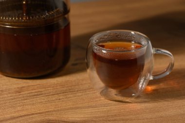 Öğlen güneşinin yumuşak parıltısıyla vurgulanmış, ahşap bir yüzeyde rahatlatıcı bir fincan çayın tadını çıkarıyorum..