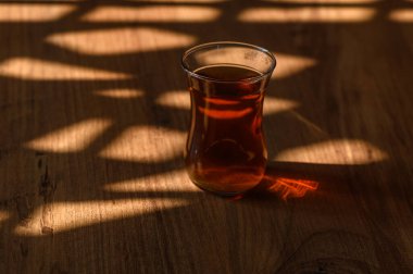 Yumuşak gün ışığıyla güzelce aydınlatılmış, kırsal ahşap bir masanın üzerinde narin bir bardak çay duruyor..