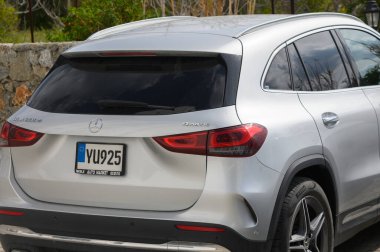 Modern gümüş rengi SUV, sakin bir açık alana park etmiş, güneşin altında güneşleniyor ve etrafı doğayla çevrili..