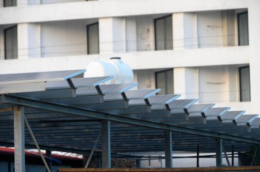 Güneş panelleri, yakınlardaki çağdaş binaların ortasındaki parlak koşullar altında enerjiyi kullanan bir yapıyı hizaya getiriyor..