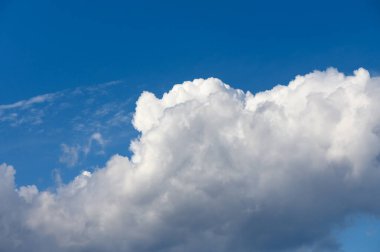 Yumuşak beyaz bulutlar açık mavi bir gökyüzünde yavaşça süzülür, güneşli bir günde huzurlu bir atmosfer yaratır..