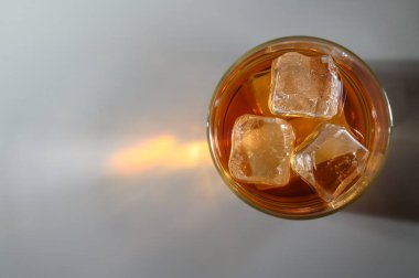 Soğuk bir içecekle dolu bir bardak, güneş ışığı altında parlayan sergilenen buz küpleri, ferahlatıcı bir yudum.