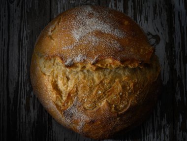 Taze pişmiş yuvarlak ekmek vitrinleri kabuklu bir üst ve rahat bir mutfak ortamında davetkar bir doku..