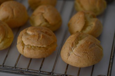 Altın kahverengi hamur çörekleri bir tel askıda serinlerken, havayı davetkar taze pişmiş ekmek aromasıyla dolduruyorlar..