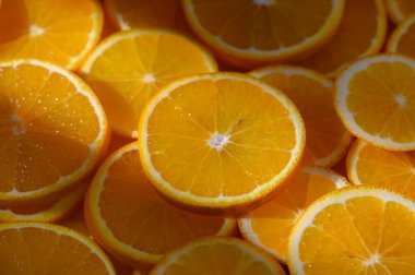 Taze kesilmiş portakallar canlı daireler şeklinde yayılmış. Çekici cazibeleri ve güneşli renkleri ile seyircileri davet ediyorlar..